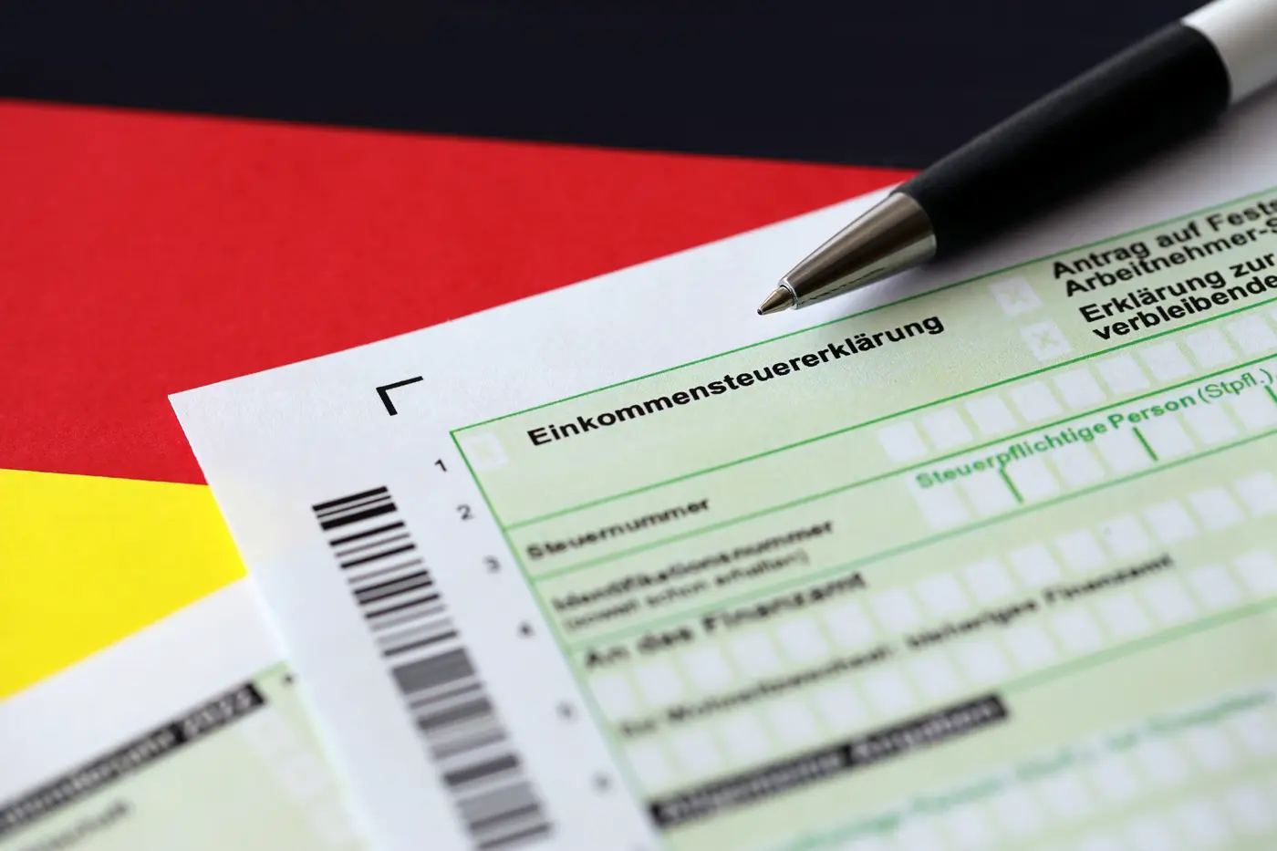 Duits belastingformulier (Einkommensteuererklärung) met een pen erop, op de Duitse vlag